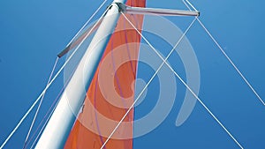 Lower angle view of a mast and mainsail with ropes of a sailing boat.