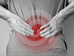 Lower back pain. Man hands holding red painful spot closeup. Sedentary lifestyle, injury, chronical illness