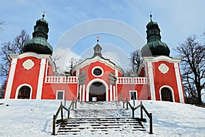 Lower baroque church on calvary in Banska Stiavnica with snow covered staircase. Photograph taken during partly cloudy winter day