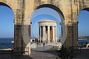 LOWER BARRAKKA GARDENS, VALLETTA, MALTA - NOVEMBER 16TH 2019: The Siege Bell War memorial seen through an archway. Built in 1992