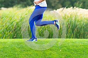 Lower body of a woman sprinting through a park