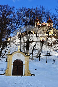 Dolní kaple banskoštiavnické kalvárie během zimní sezóny v březnu 2018, horní kostel v pozadí, zasněžený slunečný den