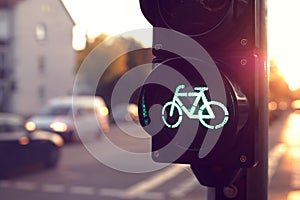 The lower half of a traffic light for a cycling lane showing green bicycle symbol stands in bright toned morning light.