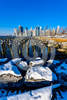 Lower Manhattan skyline panorama in snowy winter time from Brooklyn Bridge Park riverbank, New York City, USA