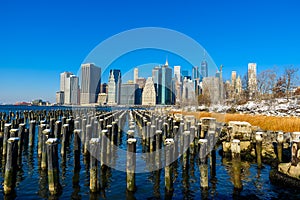 Lower Manhattan skyline panorama in snowy winter time from Brooklyn Bridge Park riverbank, New York City, USA