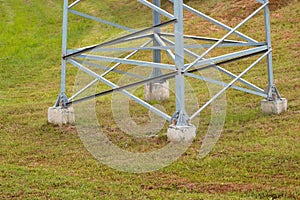 Lower part of a large electric support on a background of green grass