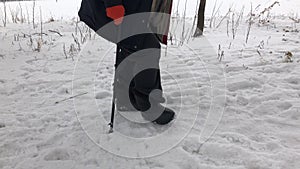 Lower part of a man wearing valenkikind of felt boots walking on a snow covered footpath