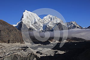 Lower part of the Ngozumba Glacier and snow covered mountains Cholatse and Tobuche, Nepal