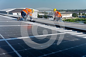 Lower view with panel as foreground, two Caucasian technician workers work with install the solar cell panels on rooftop of