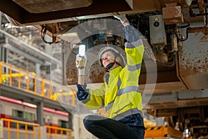 Lower view of train factory or professional technician worker check and fix the problem of the train using hold light stick and