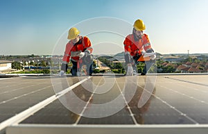 Lower view two Caucasian technician workers hold document pad and tablet check and maintenance the solar panels on rooftop of the