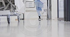 Lowsection of african american male doctor running in hospital corridor, slow motion