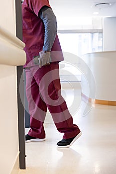 Lowsection of african american male doctor with smartphone walking in hospital corridor