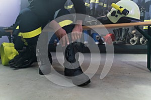 Lowsection of firefighter preparing for action in fire station at night