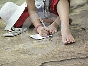 Lowsection Of Woman Writing On Paper Outdoors