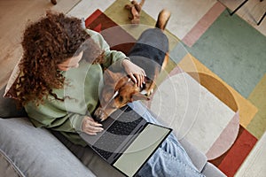 Loyal Dog Laying Head on Girl Using Laptop on Sofa at Home