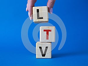 LTV - Life Time Value symbol. Concept word LTV on wooden cubes. Businessman hand. Beautiful blue background. Business and LTV