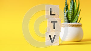 LTV - lifetime value - concept with wooden blocks on table, yellow background