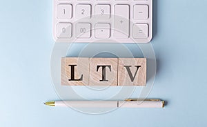 LTV on wooden cubes with pen and calculator, financial concept