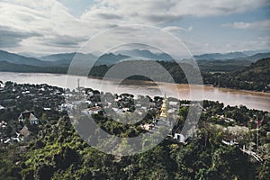 Luang Prabang, Laos. Aerial view Luang Prabang town in Laos. Cloudy sky over small city surrounded by mountains. Mekong river