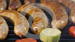 Lubricate grilled sausages with oil with a brush while frying. Close-up of a group of vegetables in smoke.