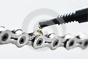 Lubricating a bicycle chain with a drop of oil close-up on an isolated gray background