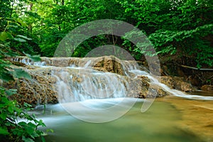 Lucansky waterfall in the village of Lucky - water flows down a travertine rock from a small height among greenery.