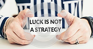 LUCK IS NOT A STRATEGY. Woman holding a card with a message text written on it