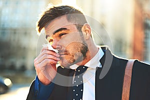 Luckily I stocked up on tissues before going out. a irritated looking young man blowing his nose with a tissue while