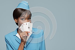 Lucky cheerful african stewardess holding four aces in her hand.