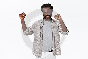 Lucky happy handsome african american bearded guy do champion dance, raising hands up, smiling cheerfully and triumphing