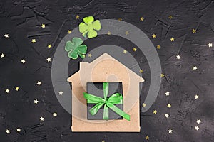 Lucky home symbol with four-leaf clover and gift on black background with stars