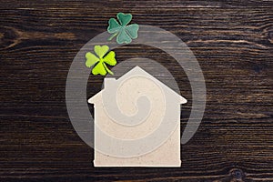 Lucky home symbol with four-leaf clover on wooden background. Co