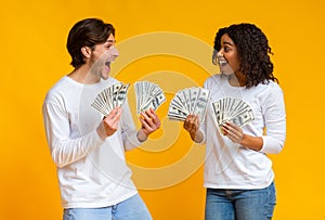 Lucky interracial couple holding bunch of dollar cash in hands