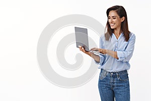 Lucky professional good-looking adult female entrepreneur writing text message coworker, smiling joyfully, hold laptop
