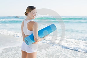 Lucky slender woman holding rolled up exercise mat