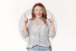 Lucky successful good-looking middle-aged 45s years redhead woman pointing up raised index fingers showing promo smiling