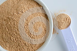 Lucuma Powder In White Bowl with Measuring Spoon