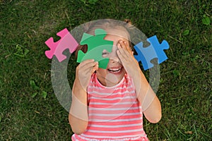 A ludicrous child is playing with puzzles while lying on the lawn grass photo