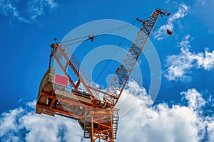 Luffing jib tower crane against blue cloudy sky.