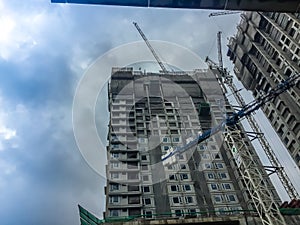 Luffing jib tower crane at high rise building construction site project. Skyscraper building under construction with the tower