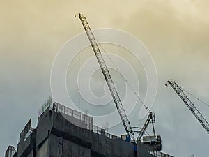 Luffing jib tower crane at high rise building construction site project. Skyscraper building under construction with the tower