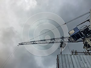 Luffing jib tower crane at high rise building construction site project. Skyscraper building under construction with the tower