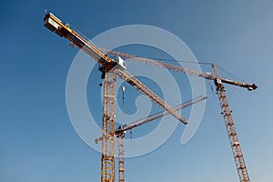 Luffing jib tower crane at large scale construction site with blue sky