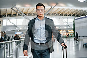 With lugagge. Young businessman in formal clothes is in the airport at daytime photo