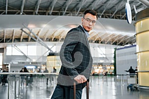 With lugagge. Young businessman in formal clothes is in the airport at daytime photo