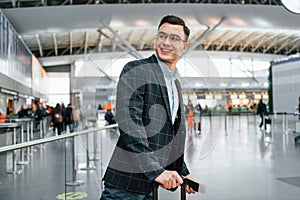 With lugagge. Young businessman in formal clothes is in the airport at daytime photo