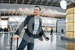 With lugagge. Young businessman in formal clothes is in the airport at daytime photo