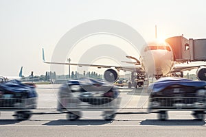 Luggage motion blurred trolley cart going fast delivering passenger baggage to modern plane on taxiway at airport on