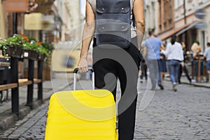 Luggage travel tourism concept, closeup of yellow suitcase in hand of walking woman